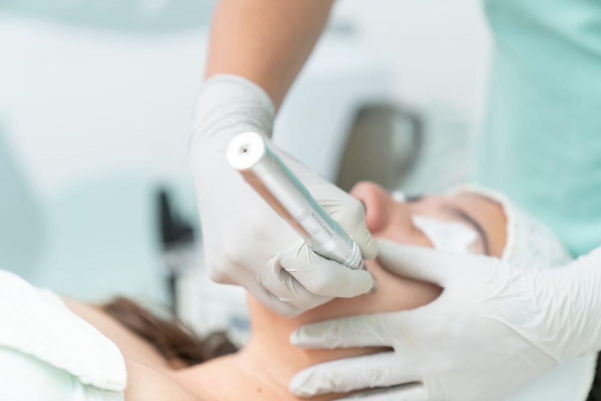 Profissional de luvas realizando procedimento estético facial em clínica