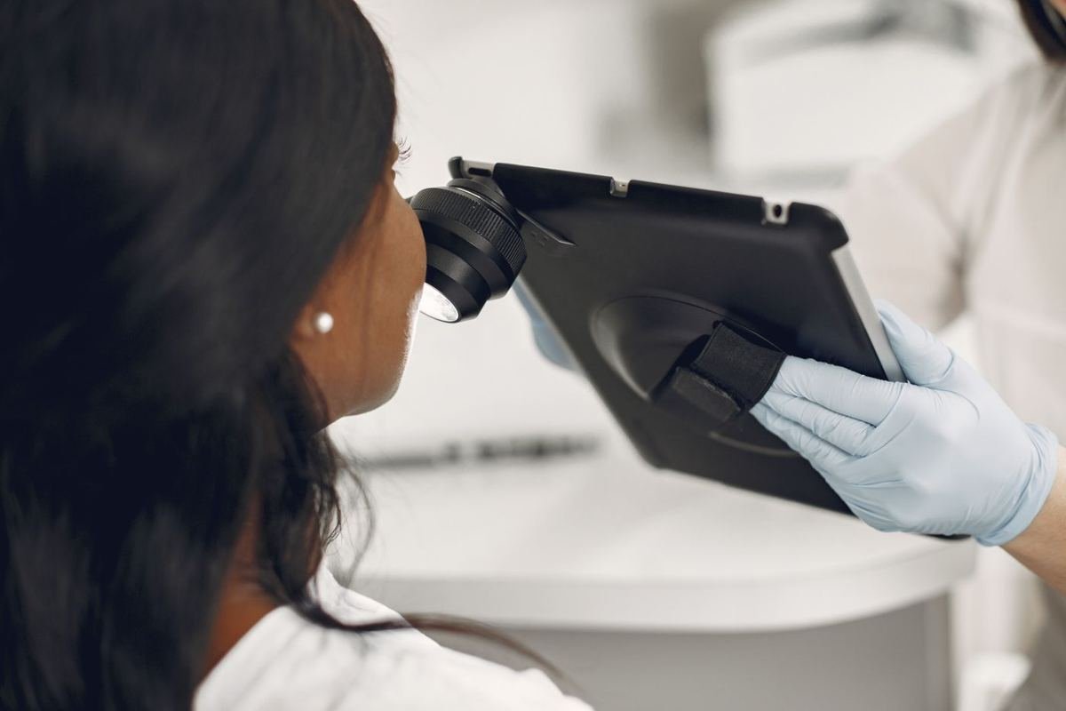 Dermatologista examinando a pele de uma paciente com dermatoscópio digital