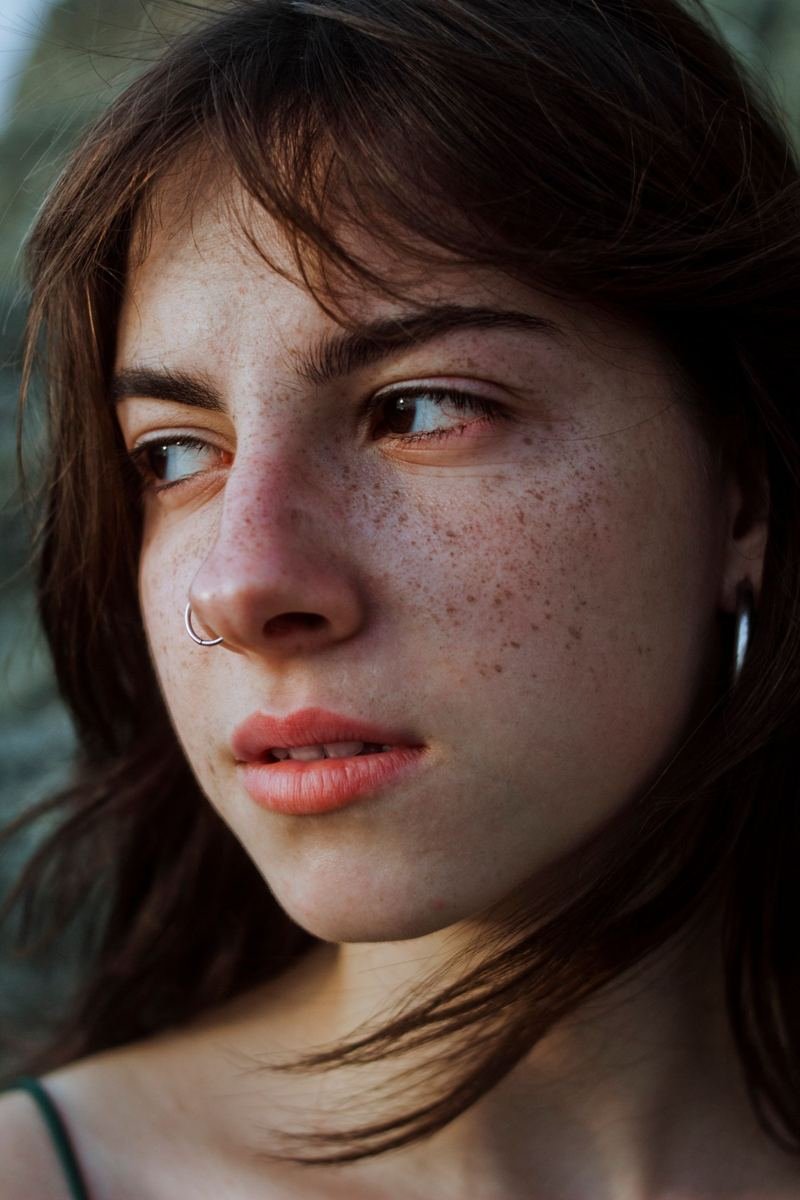 Rosto de mulher jovem com sardas, de perfil