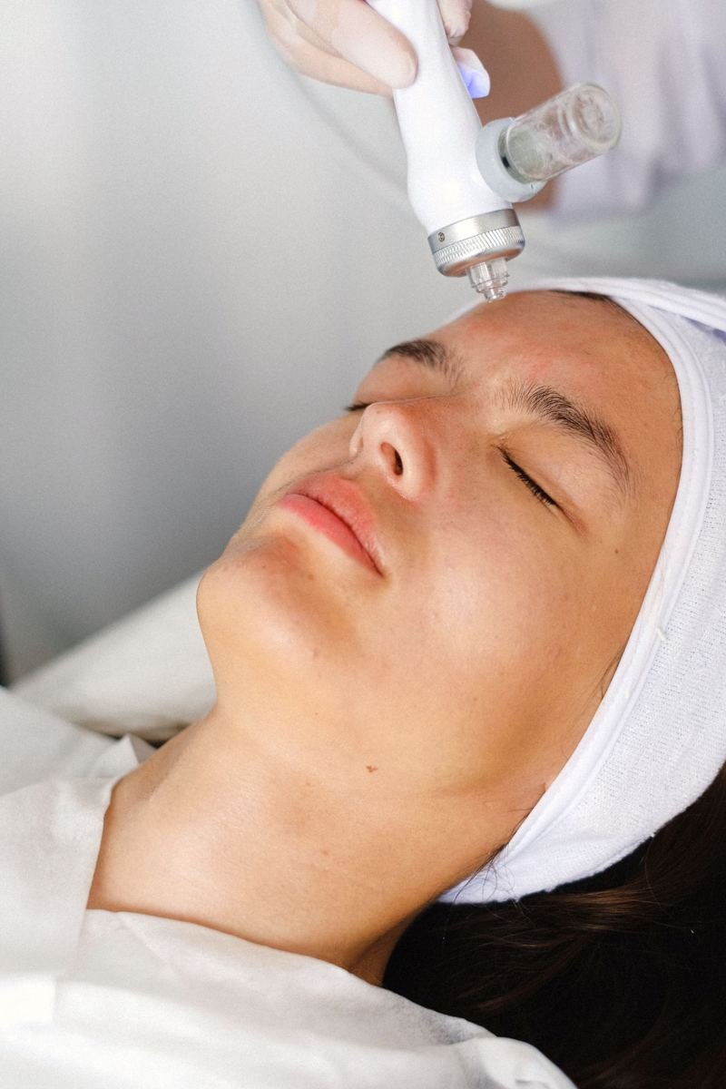 Paciente deitada recebendo tratamento facial com equipamento